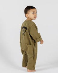 Child wearing a pistachio green jumpsuit with Crumb Text and Crumb Icon. 