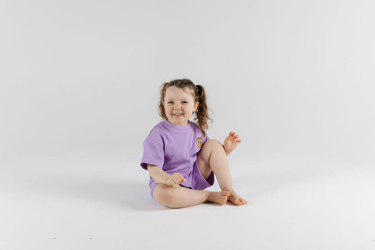 Happy child on the floor wearing Violet Crumble Drop Sleeve Set