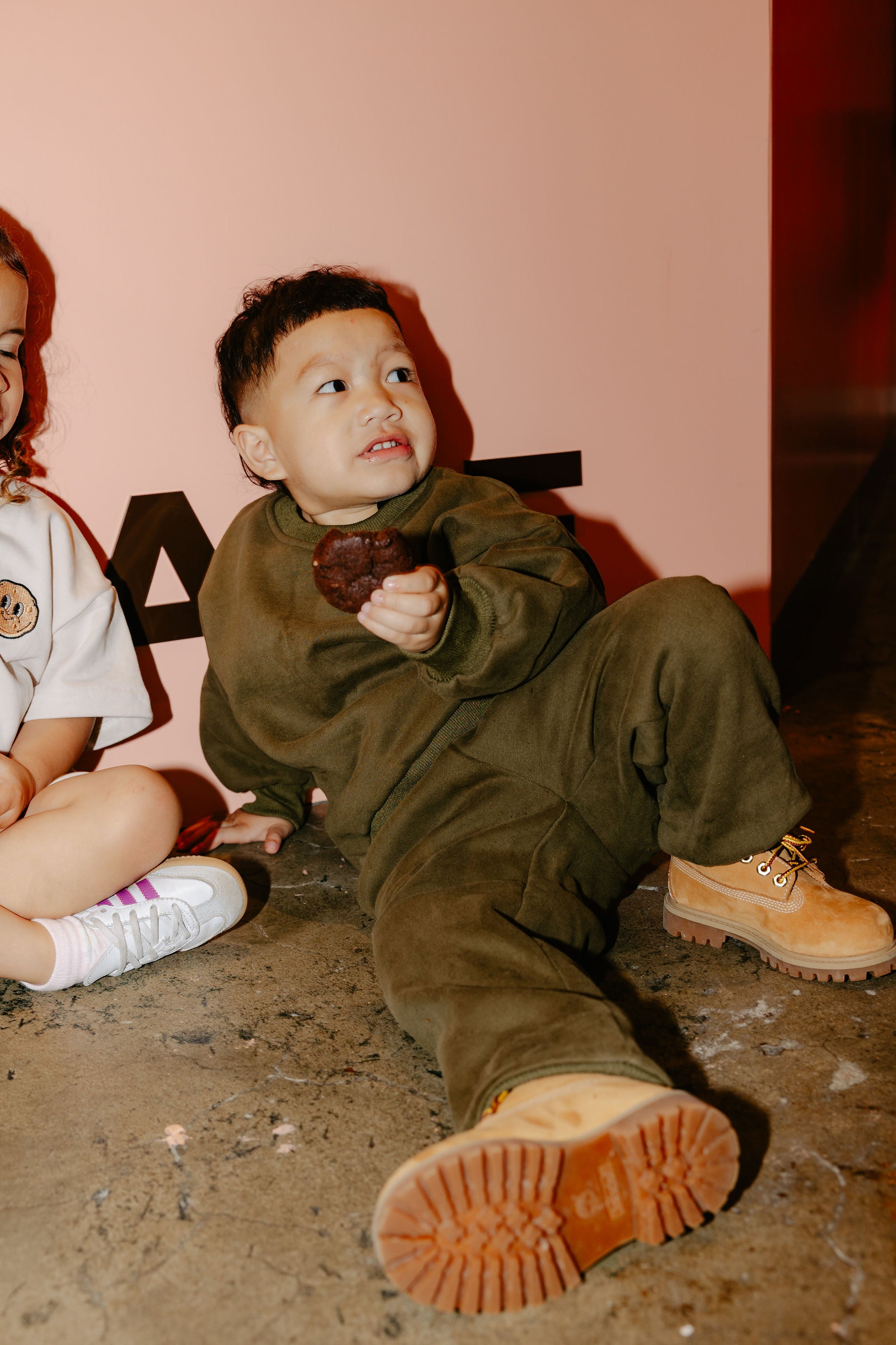 Enjoying a cookie while in Crumb's Downtown Set Pistachio Truffle kids tracksuit