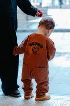 Child in a chocolate brown onesie about to go outside