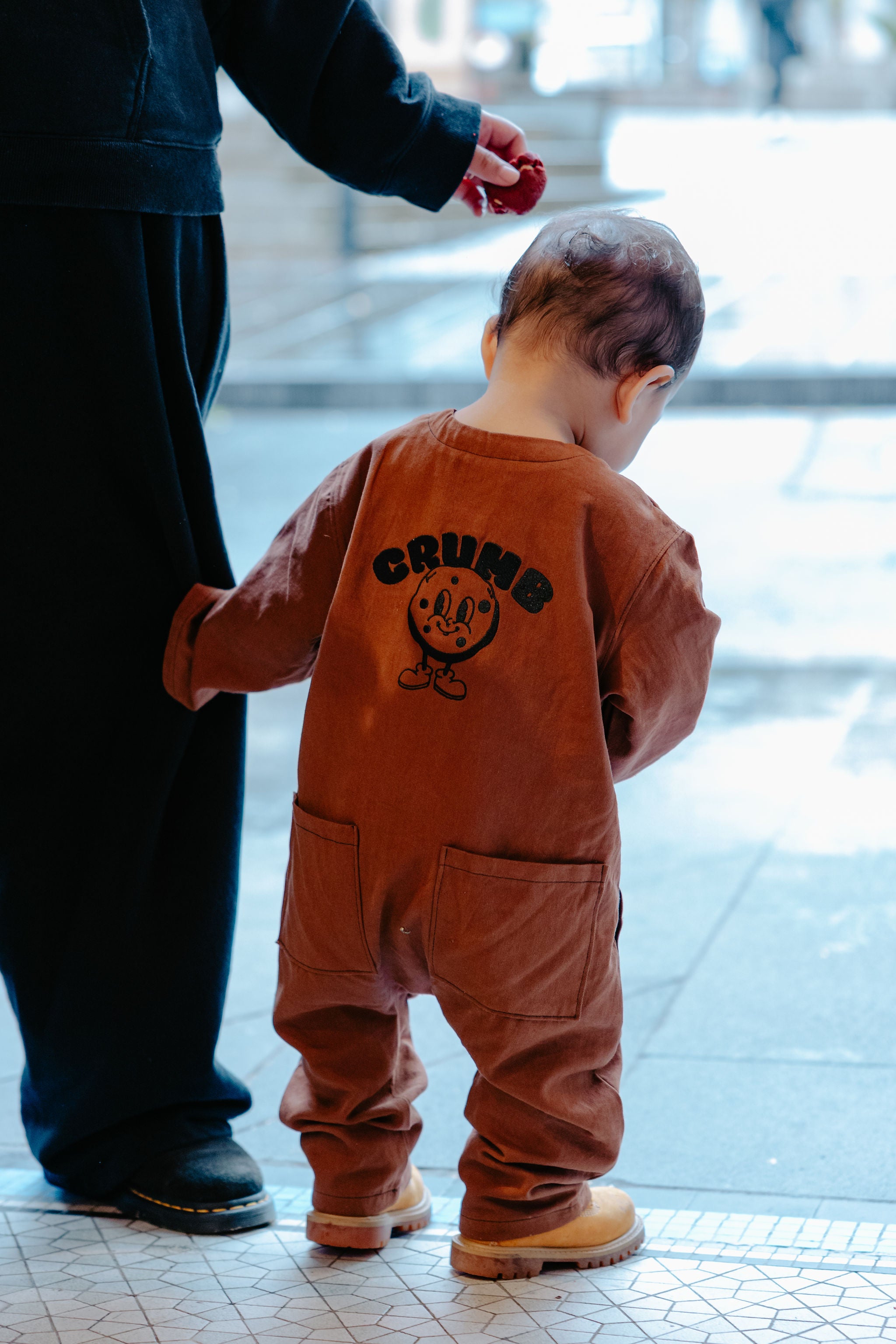 Child in a chocolate brown onesie about to go outside